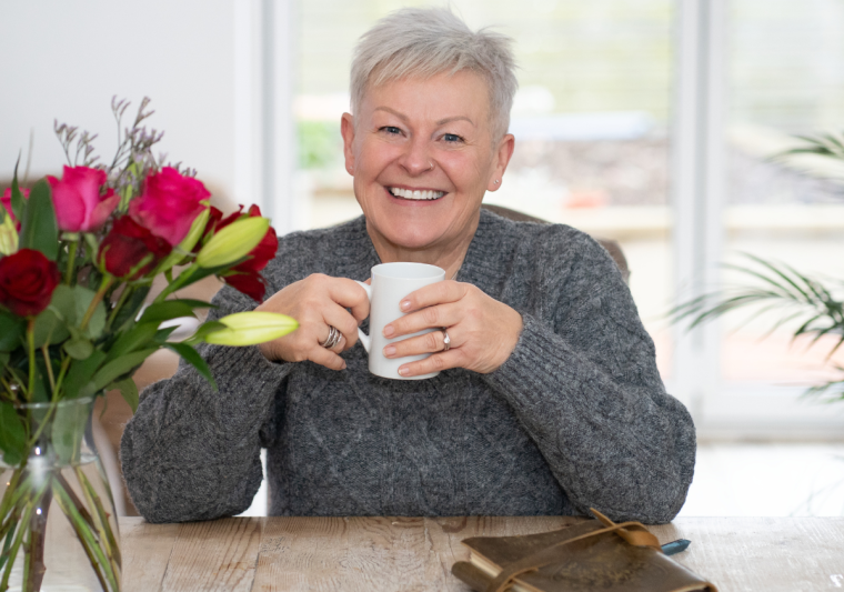 Jules at her dining table enjoying a hot drink