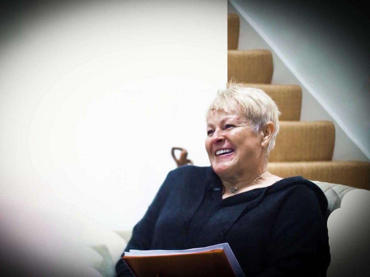 Portrait picture of jules whale laughing with her red note book.