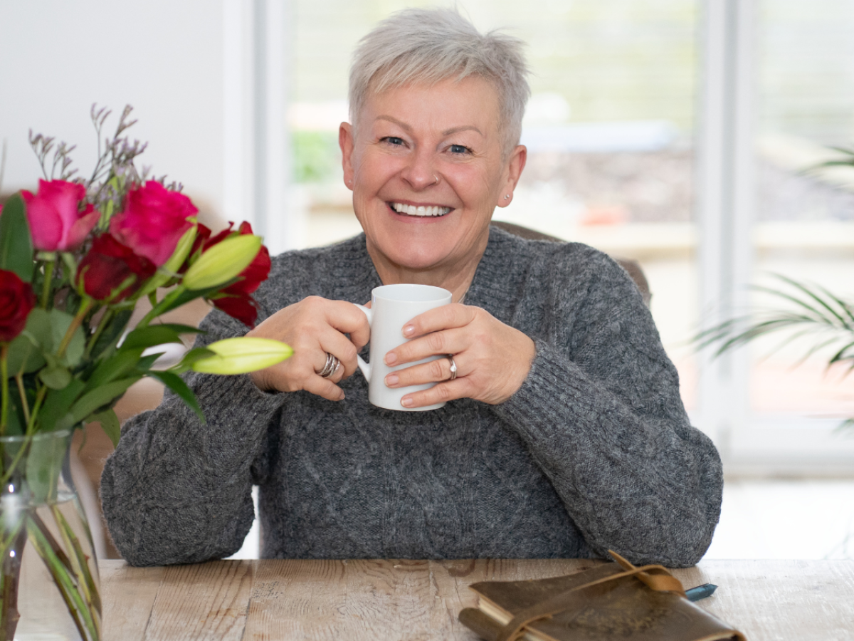Jules at her dining table enjoying a hot drink