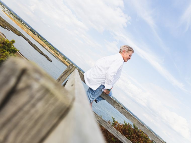 How To Ditch Your Guilt And Move On Blog Image | Jules Whale Life Coach sitting on a fence with the sea and coastline behind her in Dorset